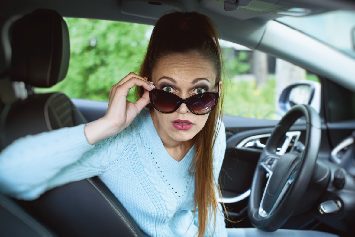 Homepage Hero Ad, woman with lowered sunglasses in a car